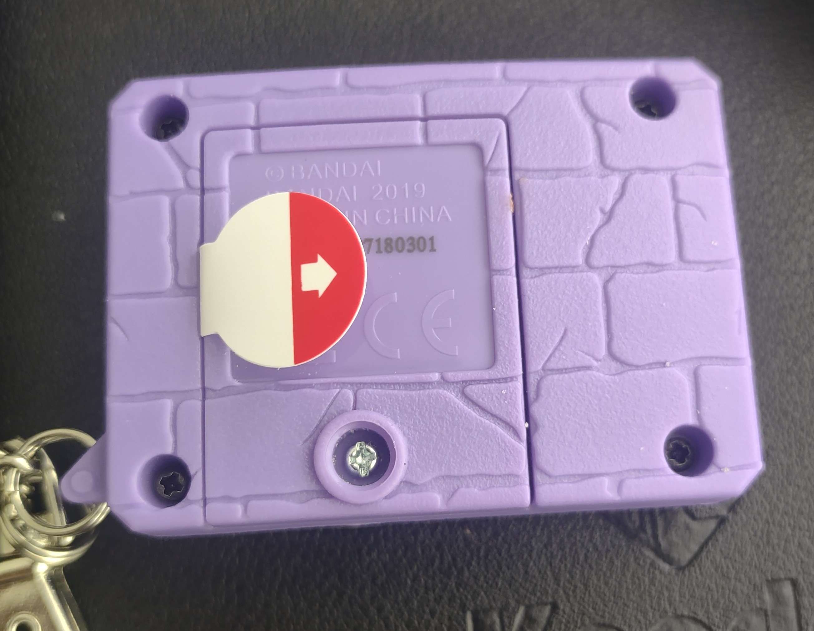 The back of a purple and red digitial monster X, which still has the pull tab in.